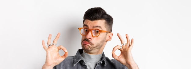 Foto non male l'uomo impressionato con gli occhiali alla moda che mostra segni ok e annuisce in segno di approvazione lodando la buona cosa mak