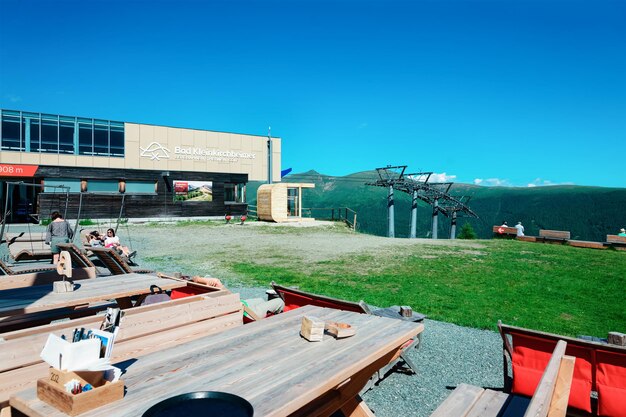 Bad Kleinkirchheim, Austria - June 28, 2019: Open air cafe with wooden tables and chairs in Alps mountains and blue sky of Carinthia. Austrian hills with Green meadow. Travel and tourism in summer