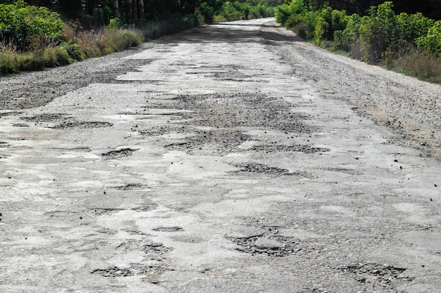 Bad road cracked asphalt with potholes and big holes potholes on the road with stones on the asphalt