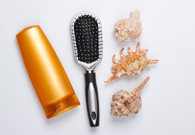 Bad schoonheidsproducten. Fles shampoo, cockleshells, haarborstel op wit. Haarverzorging