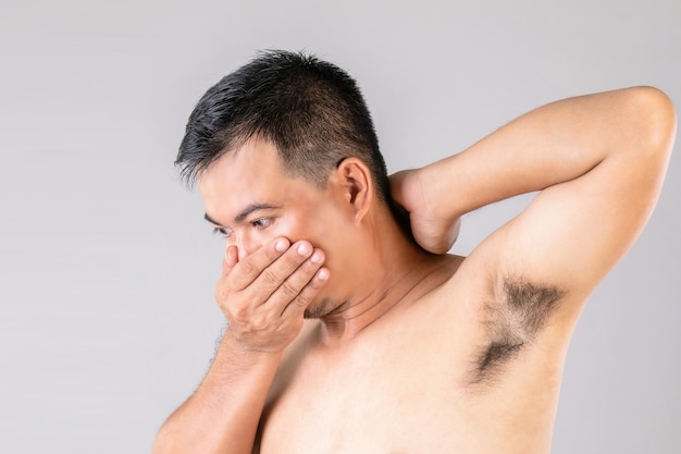 Bad smell underarm rash : Man checking and smelling his armpit.