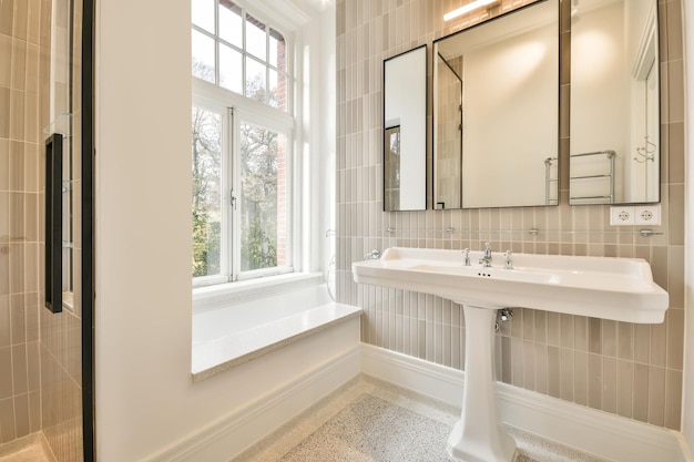 Badkamer met keramische wastafel onder de spiegel en een klein raam in een modern huis
