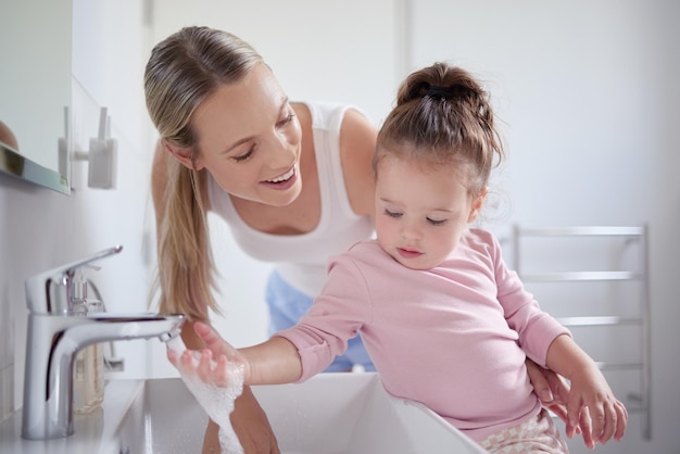 Badkamer schoon en handen wassen met kind en moeder hygiëne onderwijzen met stromend kraanwater in bassin Gezinsgezondheid en bescherming tegen virussen met moeder en baby die een schoonmaakroutine leren