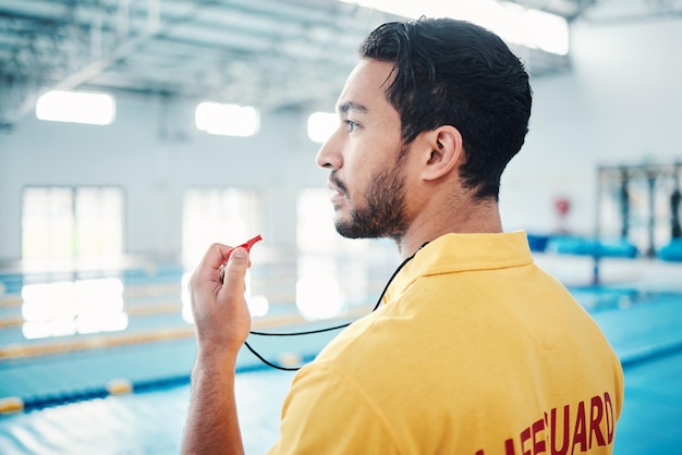 Badmeesterfluitje en zwembadveiligheid door man die kijkt naar binnenfaciliteit voor training, zwemmen en oefenen Badmeester en man watersporter die toezicht houdt op oefeningsgevaar en zwemmer