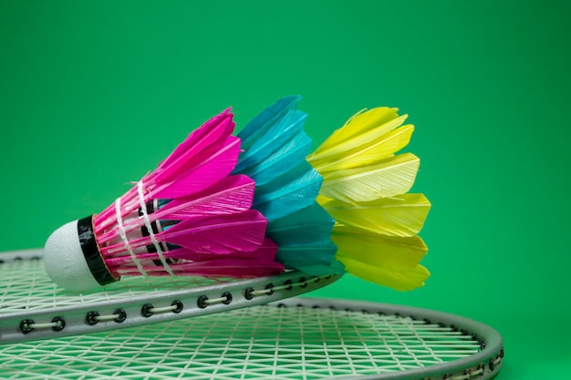 Foto racchette da badminton e volani piumati colorati in blu giallo e rosa su sfondo verde