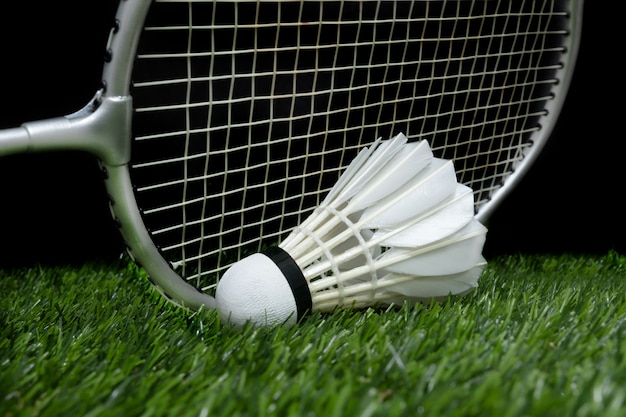 Badminton shuttlecock on grass with racket