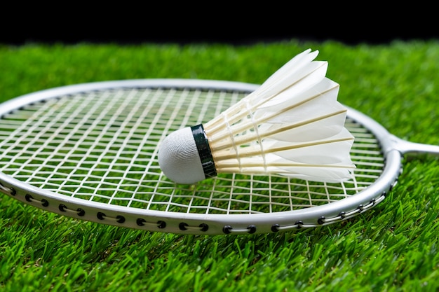 Badmintonbal en racket op gras op zwarte achtergrond