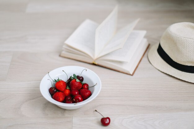 Badpakhoedenboek en verse zoete kersen en aardbeien op houten oppervlak