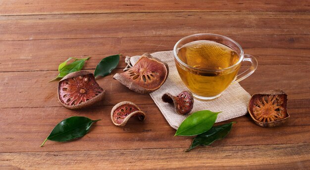 The Bael fruit juice in a glass and dried Bael fruit placed on the wooden