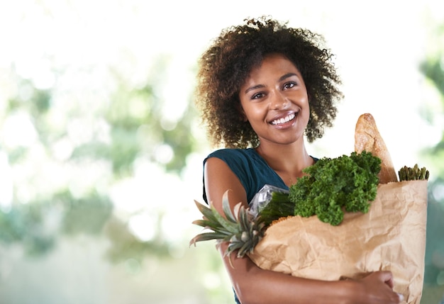 Bag of health Young girl smiling while holding her groceries isolated