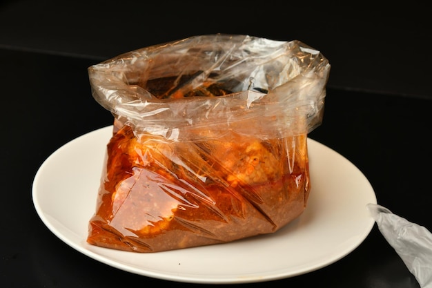 A bag of meat is on a plate with a black background.