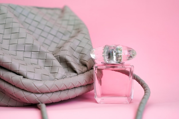 Bag on a pink background. Leather bag and perfume bottle.