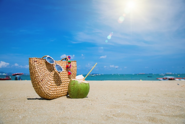 Bag, sun glasses and coconut on a tropical beach