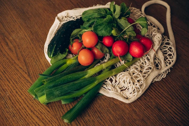 テーブルの上に野菜の入った袋があり、その上に緑の葉物野菜が置かれている。