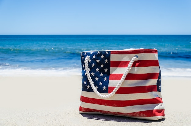 Фото Сумка с цветами американского флага возле океана на песчаном пляже