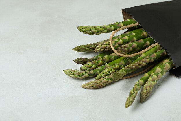 Bag with green asparagus on white textured