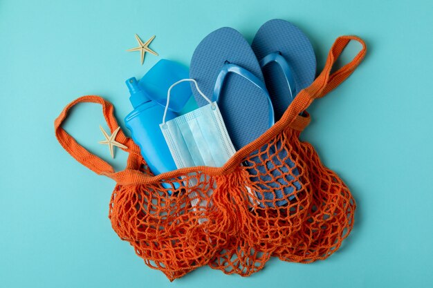 Bag with sea accessories, sunscreen and mask on blue