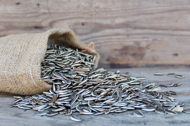 Bag with variety of sunflower seeds on rustic wooden board