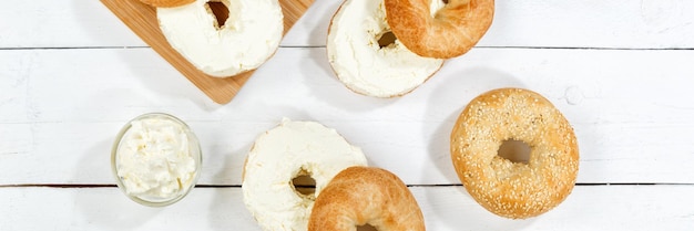 Bagel sandwich with cream cheese for breakfast from above panorama on a wooden board