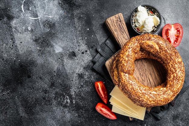 Bagel Simit or Gevrek on wooden board for cooking sandwich. Black background. Top view. Copy space.