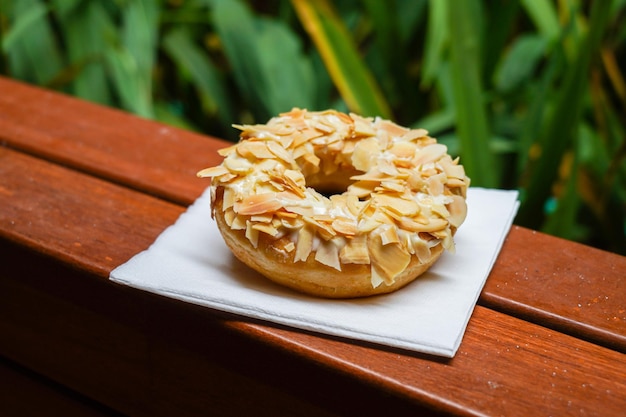 A bagel with almonds on it sits on a napkin.