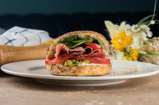 Bagel with salami with herbs and tomatoes.