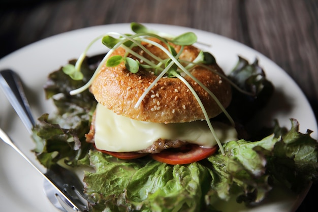 Bagel with steak and cheese on wood background