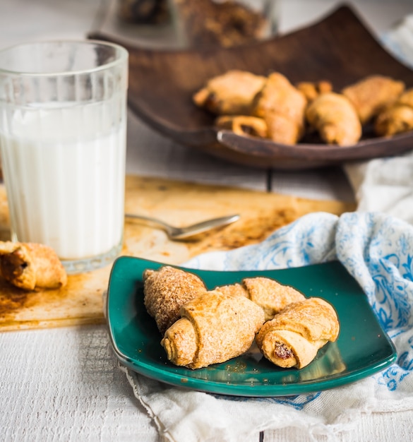 Bagels biscuits from short pastry stuffed with condensed milk in a wooden plate, a glass of milk