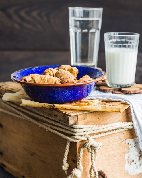 Bagels koekjes van een zanddeeg met vulling, melk, in de blauwe plaat zoete gebakjes op een houten