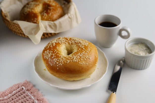 白い背景のブラックコーヒーのカップとベーグル朝食の食事の概念