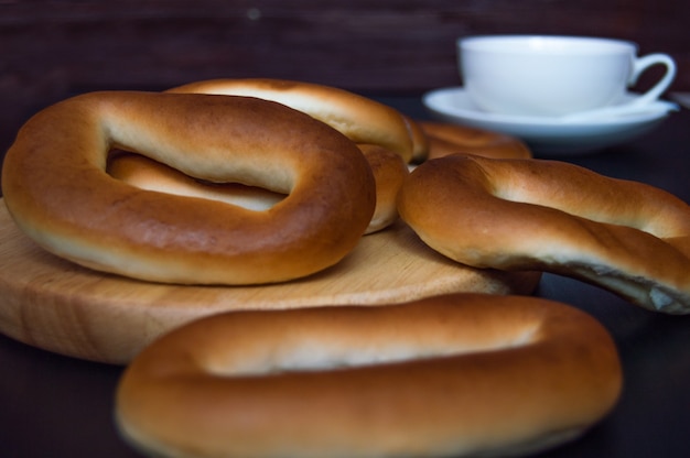 bagels on a wooden stand in front of a cup on a dark background