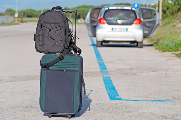 Foto bagagli in strada con un'auto aperta sullo sfondo