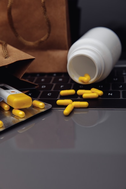 Bags with pills and drugs on a laptop keyboard. Shopping online concept. Vertical image.
