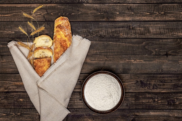 Baguette on a black background with ears of wheat and flour