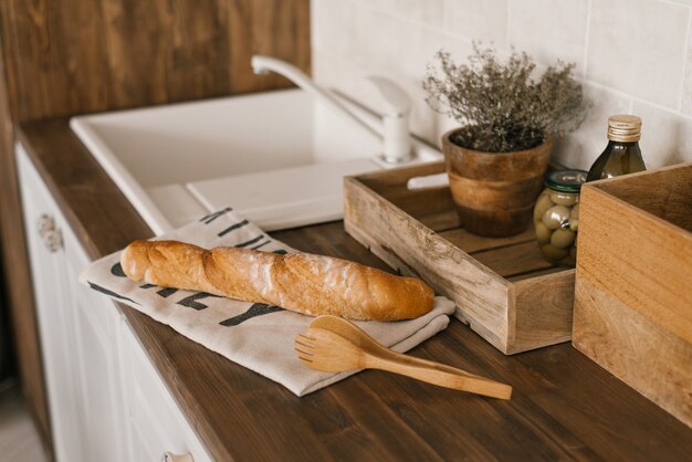 The baguette is lying on a linen towel on the kitchen table