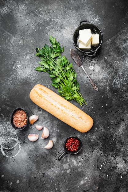 Baguette parsley herbs butter ingredients set, on black dark stone table background, top view flat lay, with copy space for text