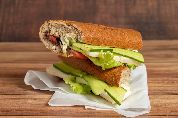Foto sandwich a baguette sandwich con olive lattuga pomodoro cetriolo cheddar e formaggio feta su sfondo di legno