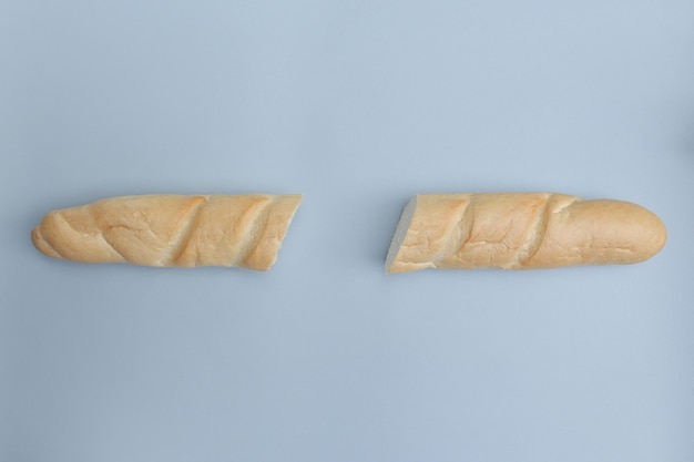 Багет из белого хлеба на голубом фоне Две половинки