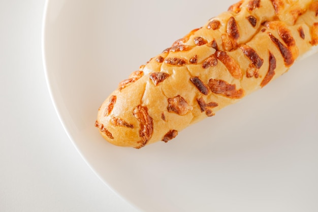 Baguette with baked cheese on white plate board background selective focus