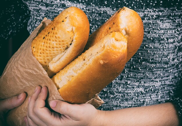 Baguettes in a paper bag in hands