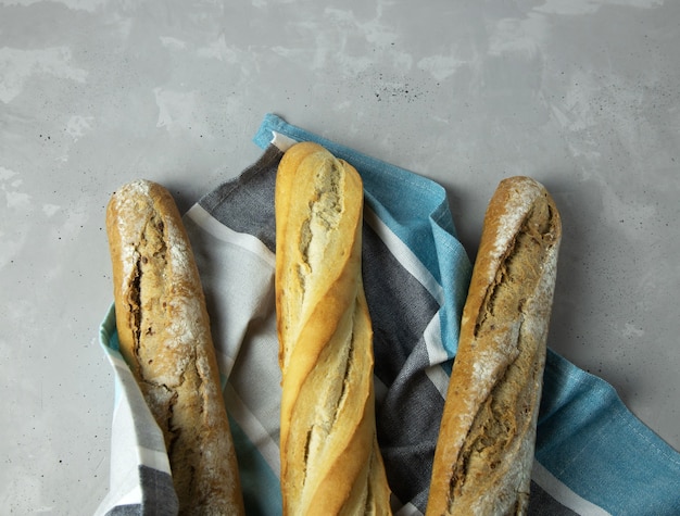 Foto baguettes, volkoren granen en gewoon, liggen op een blauwgrijs servet op een grijze betonnen tafel