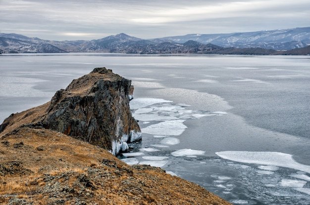 Baikal Lake en rock in de koude december. Tijd van bevriezing. IJsschotsen zwemmen op het water