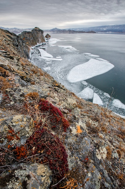 Baikal Lake and rock in the December cold. Time of freeze-up. Ice floes is swiming on the water