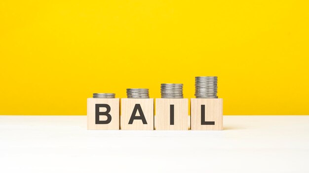 Bail text written on wooden block with stacked coins on yellow background business concept