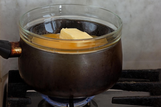 Bainmarie with sugar butter and honey in glass bowl on saucepan as ingredients of cake medovik on stovetop