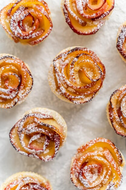 Baked apple pies in form of roses with cinnamon and cloves on a baking pan Selective focus