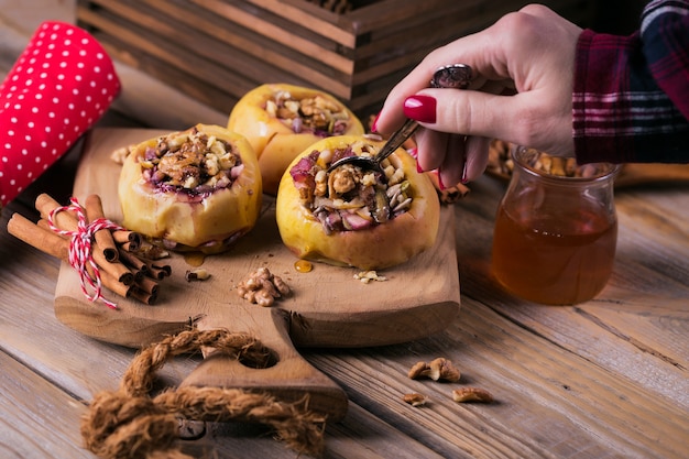 Baked apples stuffed with berries, walnuts and honey on a wooden cutting board.