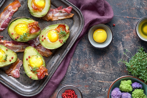 Baked avocado with egg and bacon on a metal baking tray