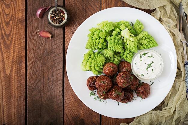 Baked beef meatballs and garnish from boiled cabbage romanesko