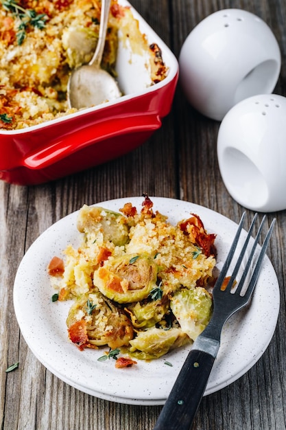 Baked brussel sprout gratin with a bacon and bread crumbs on wooden background